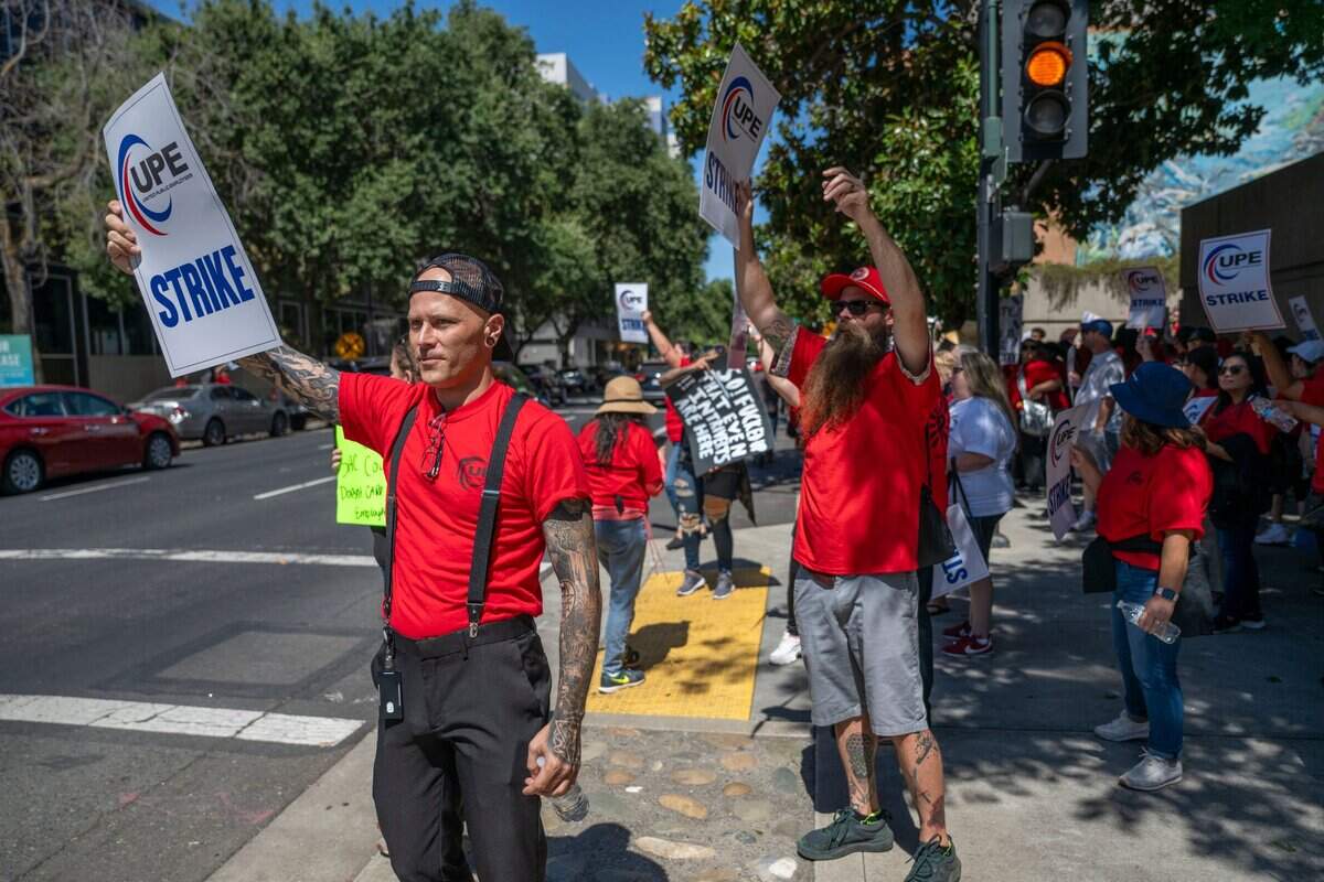 Andrew Lamb, left, a Sacramento County employee and a member of the United Public Employees union, holds a sign during a one-day strike for a pay increase at the Sacramento County Administrative Building in downtown Sacramento on Tuesday.