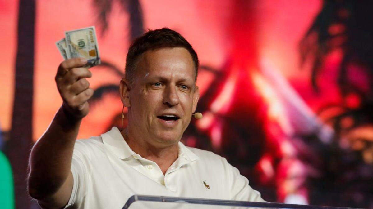MIAMI, FLORIDA - APRIL 7: Peter Thiel, co-founder of PayPal, Palantir Technologies, and Founders Fund, holds hundred dollar bills as he speaks during the Bitcoin 2022 Conference at Miami Beach Convention Center on April 7, 2022 in Miami, Florida. The worlds largest bitcoin conference runs from April 6-9, expecting over 30,000 people in attendance and over 7 million live stream viewers worldwide.(Photo by Marco Bello/Getty Images)