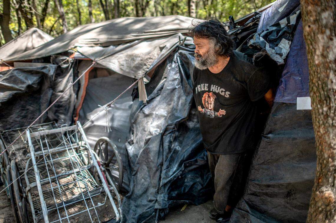 Anthony Pablo, 52, wears a “free hugs” shirt as he comes out of his tent on “the island” along the Sacramento River near Discovery Park on July 6.