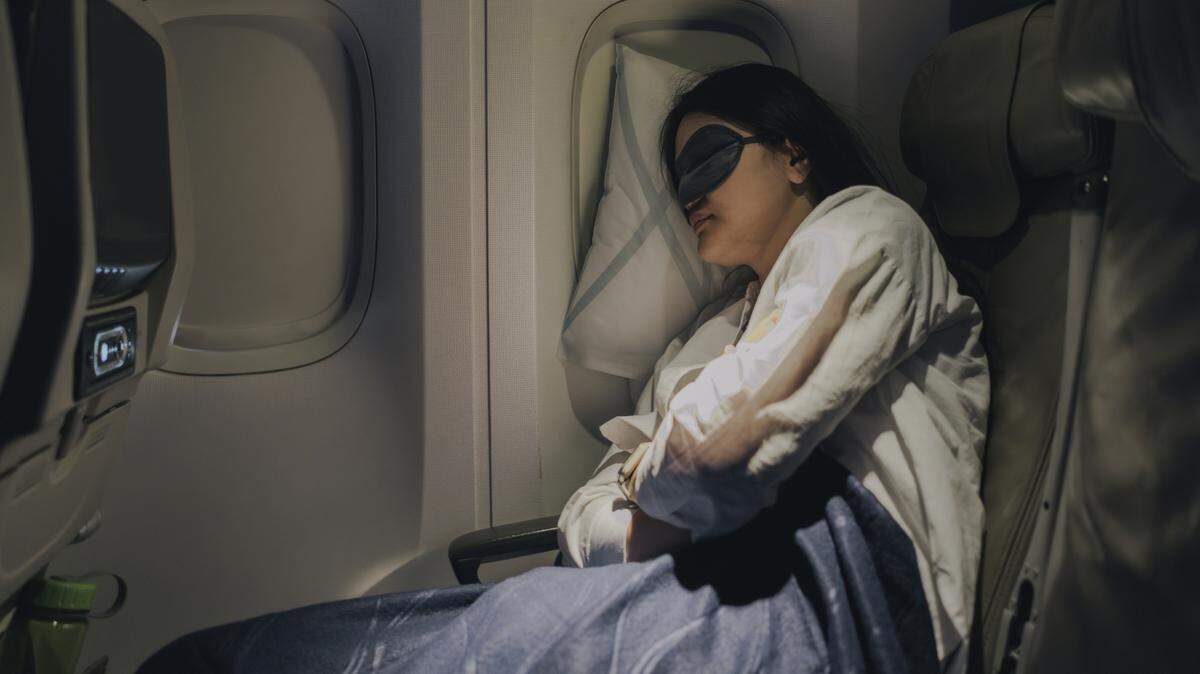 With her mask on to help her sleep, the woman gets good, deep sleep during her flight.