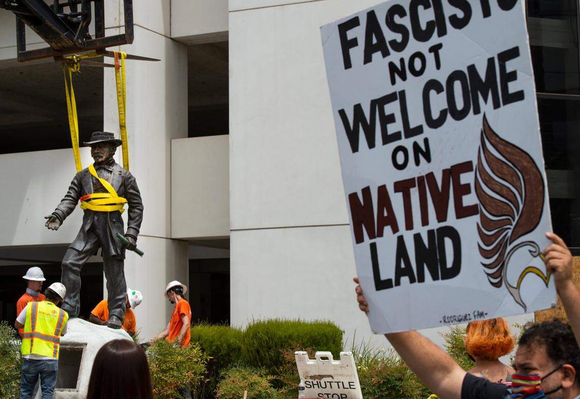 California Native American Larry Rodriguez, right, holds up a sign while workers remove a statue of John Sutter, a Swiss settler who built the first European settlement on the site of the city of Sacramento, outside Sutter hospital in midtown on Monday, June 15, 2020. “It’s a glorious day,” Rodriguez said. Some historical accounts describe Sutter as using Native Americans as slaves and raping Native American girls as young as age 12.