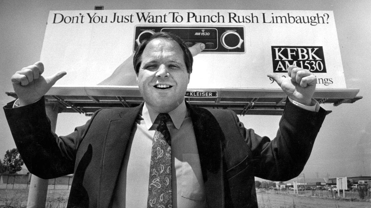 Rush Limbaugh, then a KFBK AM morning radio personality, guestures on Aug. 8, 1986, to a Sacramento billboard promoting his local talk radio show that was already reflecting the divisive conservatism he would later take nationwide.