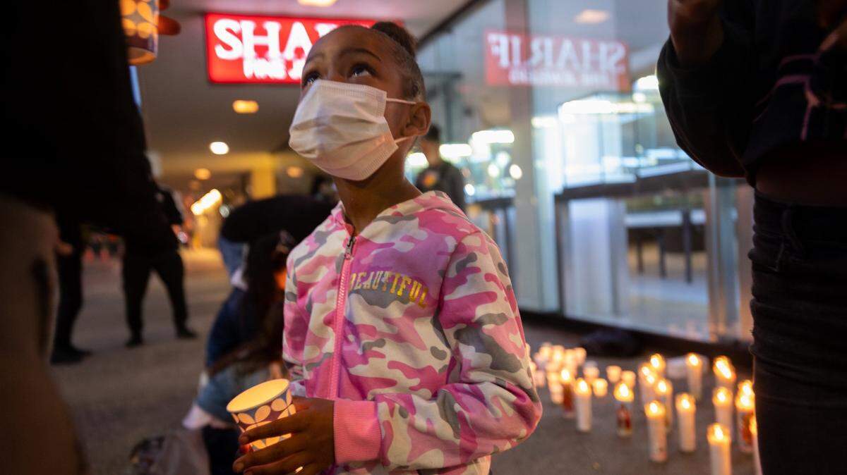 Malaya Harris, 7, holds a candle for her father, Sergio Harris, with family members at a memorial for him at 10th and K streets in Sacramento, in 2022. Sergio Harris was killed during a mass shooting that left six people dead and 12 injured.
