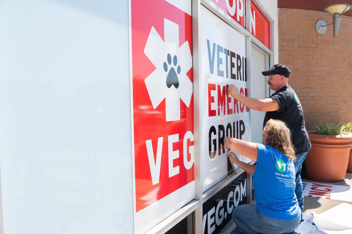 Sign installers Jennifer Heath, front, and Rick Prather put up a sign in the Veterinary Emergency Group’s hospital window announcing the new location’s opening in Elk Grove on Wednesday.