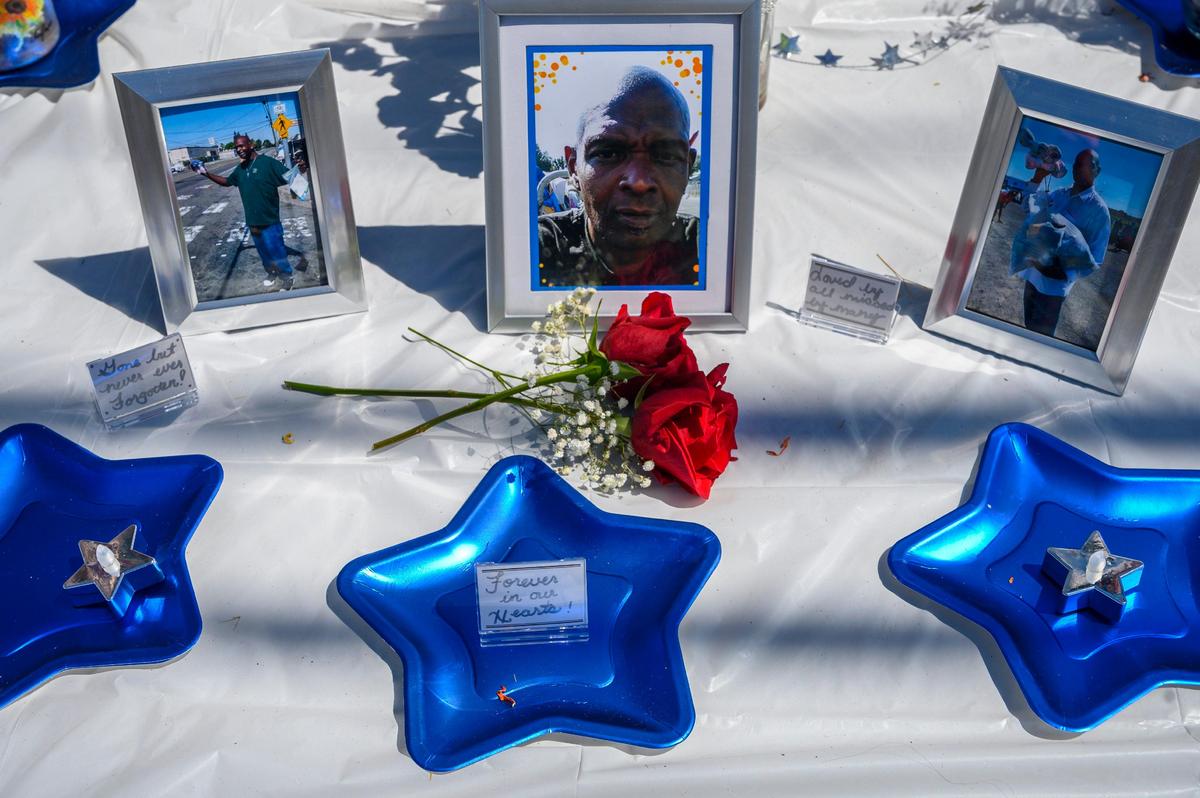 Roses are left alongside pictures of Andre Royster, a homeless advocate who was once homeless, at a memorial near B and Ahern Street on Friday, July 26, 2019 in Sacramento.