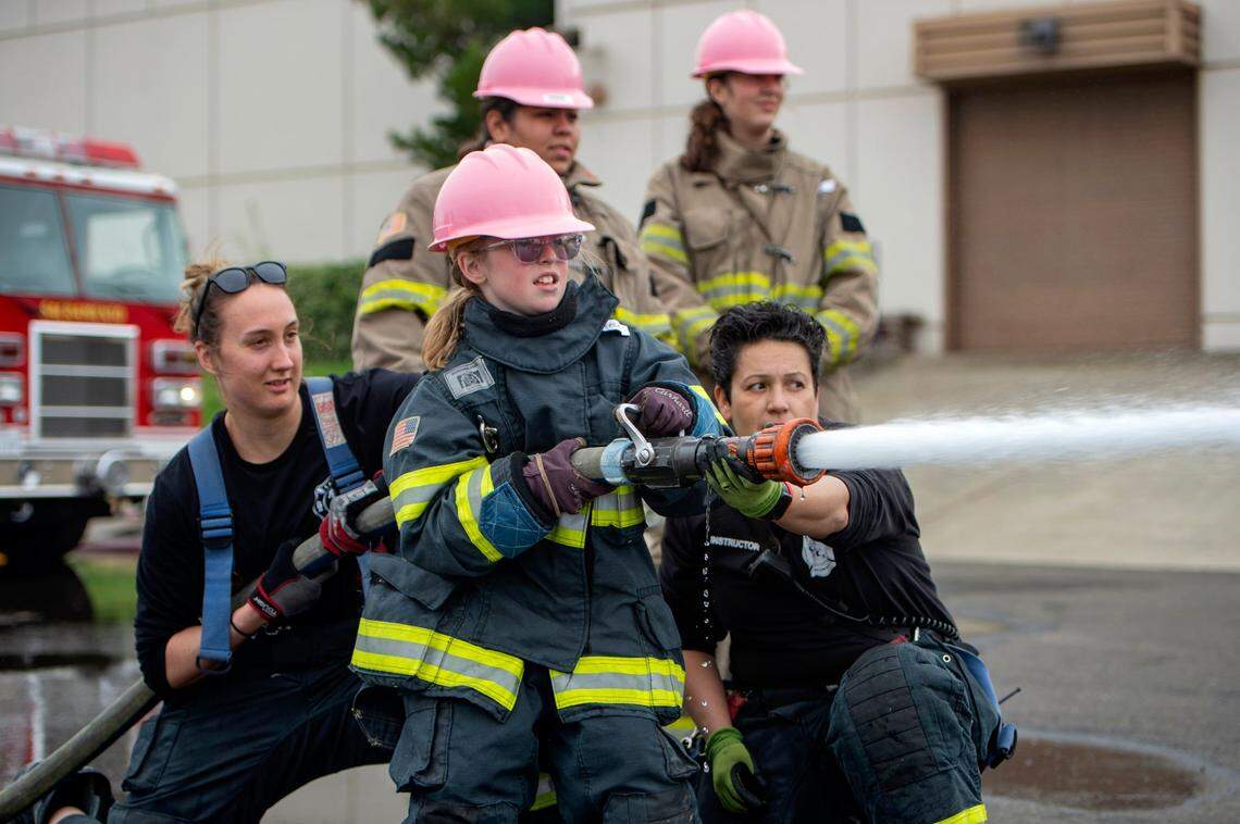 Reese Blankenship, 10, sprays water at inflatable animal targets as camp instructors help to control the fire hose at the Sacramento Area Girls Fire Camp at McClellan Park on Saturday, Oct. 23, 2021.