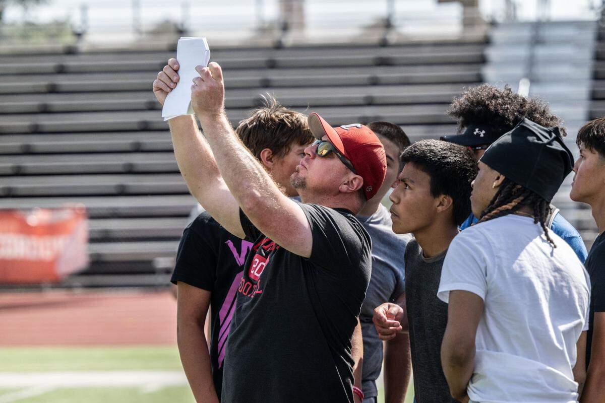 JP Dolliver, head coach for the Cordova High School football team, shows his offense a play during spring training on Monday, May 20, 2024.