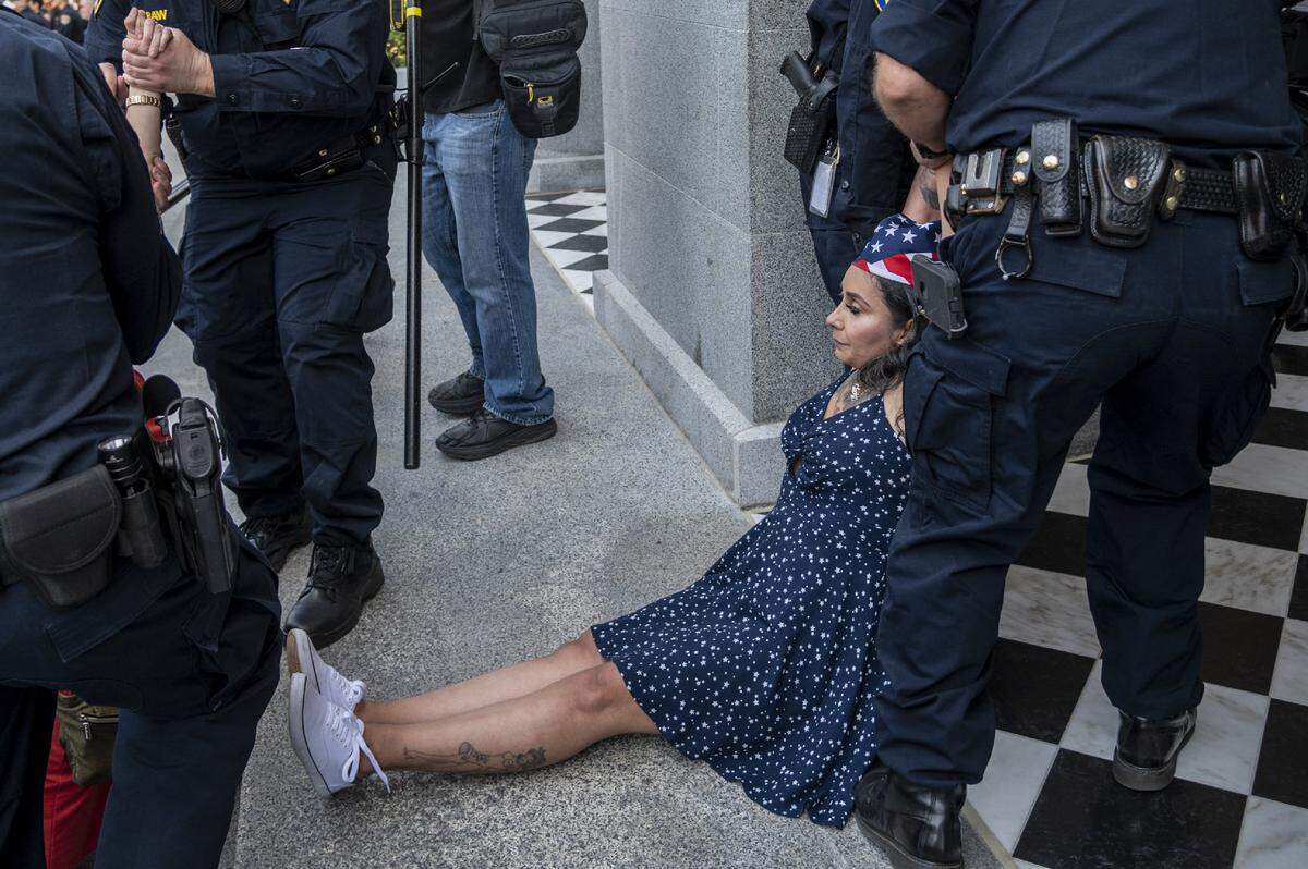 A protester is detained at the Capitol in Sacramento on Friday, May 1, 2020, while demonstrating against Gov. Gavin Newsom’s stay-at-home order to slow the spread of the coronavirus.