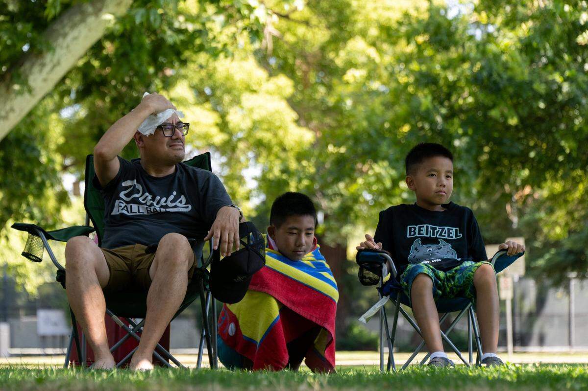 Van Tran wipes the sweat from his head while sitting in the shade on a 103 degree day in Sacramento on Friday, June 30, 2023, with his sons Levi, 11, and Gavin, 8, after a swim at Clunie Pool to cool off. The National Weather Service Heat Advisory remains in effect until 11 p.m. Sunday.