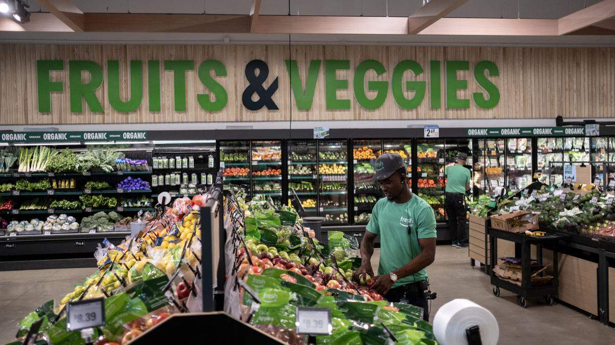 An Amazon Fresh employee stocks produce inside the high-tech grocery store.