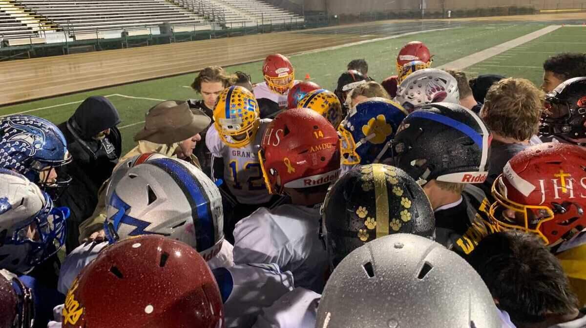 Wearing a brown hat to shield him from the rain, North Optimist All-Star coach John Volek addresses his team, including grandson Cade Brownholtz, back in red helmet, during a practice Tuesday, Jan. 15, 2019, at Sacramento State.