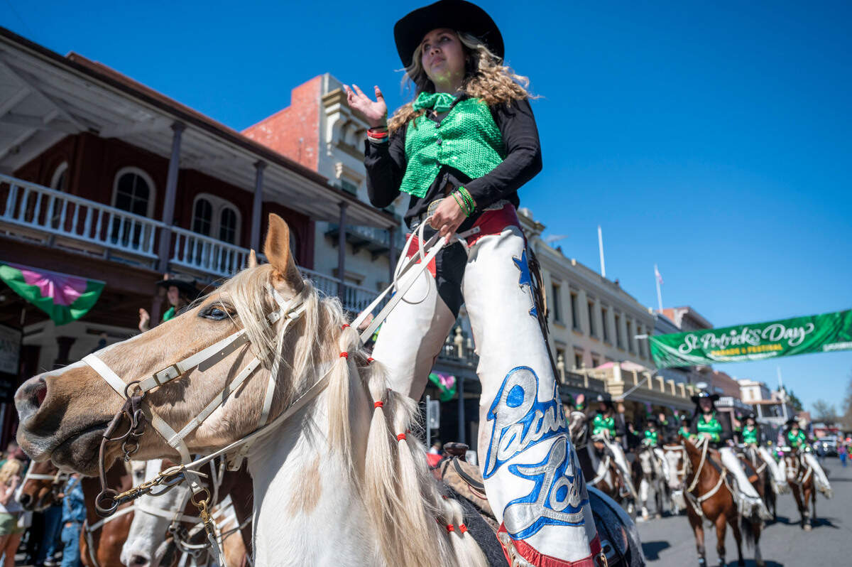 Kallie McCarthy stands in the saddle while riding with the Painted Ladies Rodeo Performers during the St. Patrick’s Day parade in Old Sacramento on Saturday.