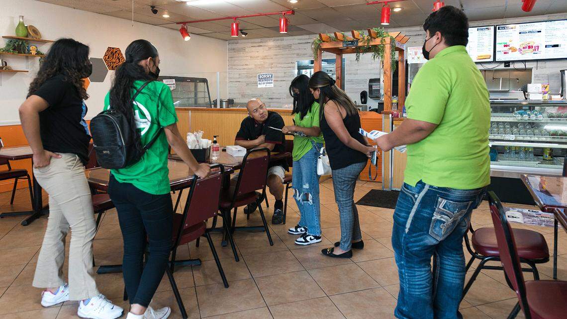 Teens deliver COVID-19 tests and information flyers to Chris Vang, seated, owner of Tiger Bite Bowls, an Asian fusion restaurant in Fresno. The teens have been trained as health educators to promote COVID-19 vaccinations.