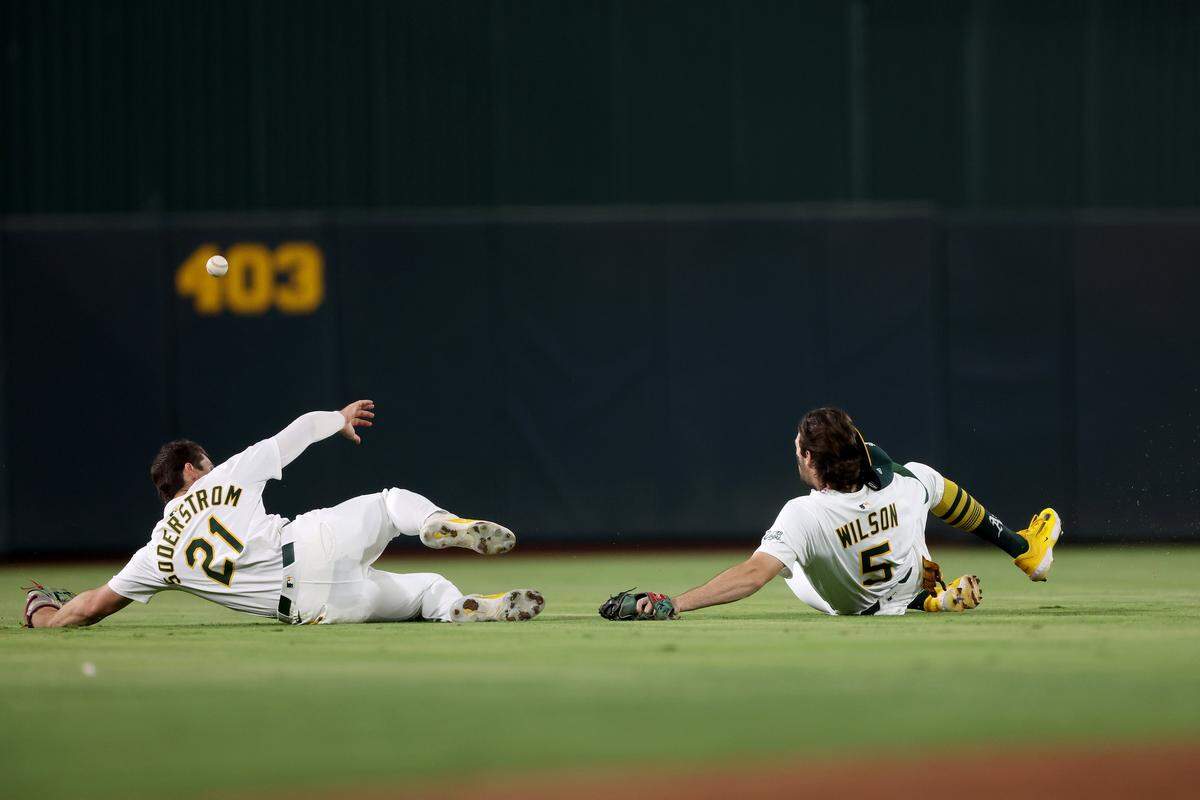Athletics left fielder Tyler Soderstrom (21) and shortstop Jacob Wilson (5) slide to avoid a collision while chasing a fly ball against the Kansas City Royals during the fifth inning Saturday at Sutter Health Park in West Sacramento.