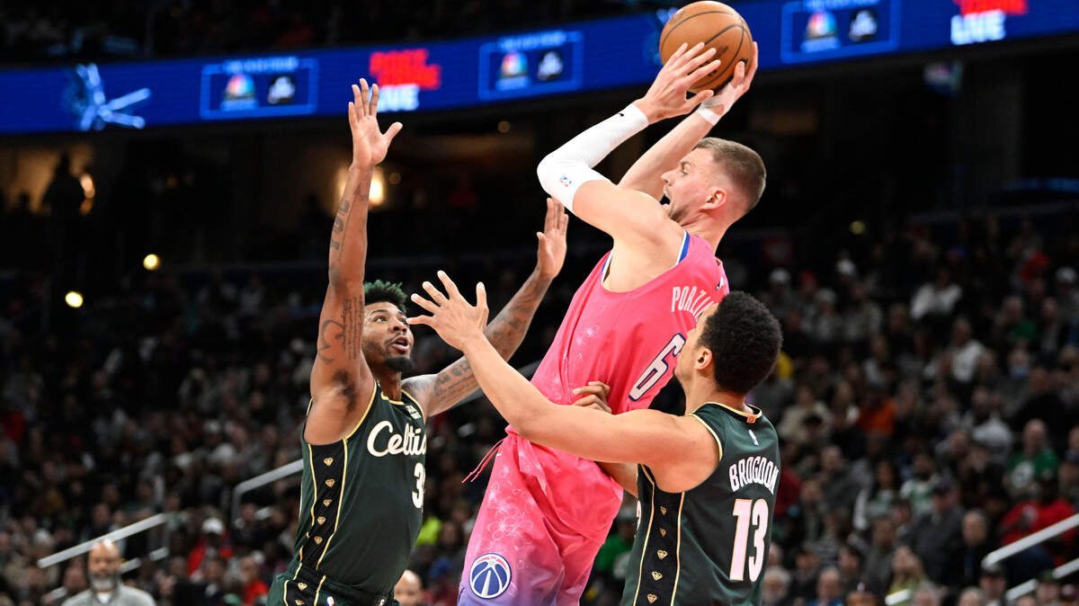 Washington Wizards center Kristaps Porzingis (6) looks to pass between Boston Celtics guard Malcolm Brogdon (13) and guard Marcus Smart (36) during the second half on March 28, 2023, at Capital One Arena in Washington, D.C.