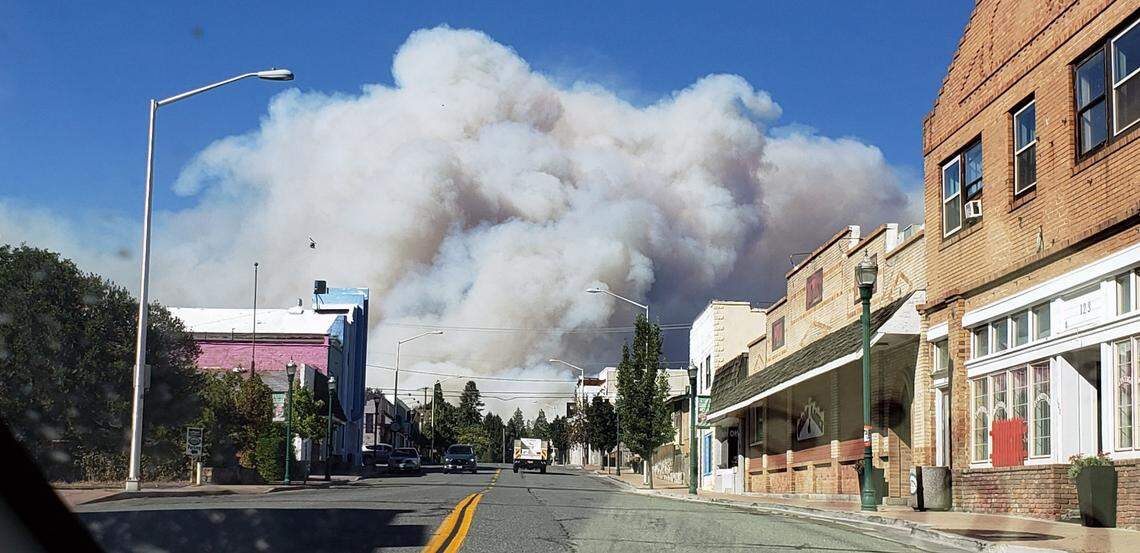 A plume of smoke covers the sky as the the Mill Fire burns near the town of Weed on Friday.