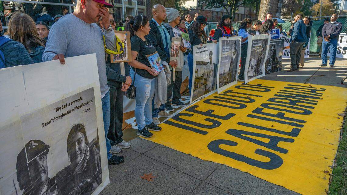 Jesus Prieto, left, of Sacramento, wipes tears as he holds a poster with his photograph as he joins hundreds before marching to opposing mass deportations and protect immigrant Californians at the state Capitol on Monday, Dec. 2, 2024. On the ground, a yellow flag calls for the removal of the federal Immigration and Custom Enforcement agency, or ICE, from the state.