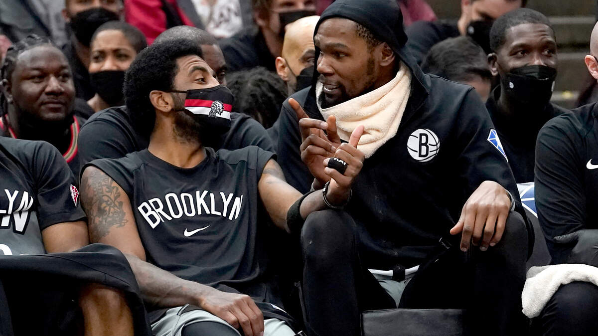 Brooklyn Nets’ Kyrie Irving, left, and Kevin Durant talk on the bench during the second half of an NBA basketball game Wednesday, Jan. 12, 2022, in Chicago. (AP Photo/Charles Rex Arbogast)
