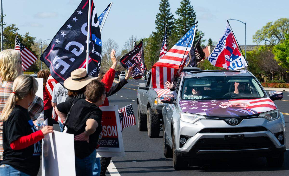 A convoy of Trump supporters drives past MAGA counter protesters on Granite Drive in Rocklin across from the Tesla dealership on Saturday, March 29, 2025.