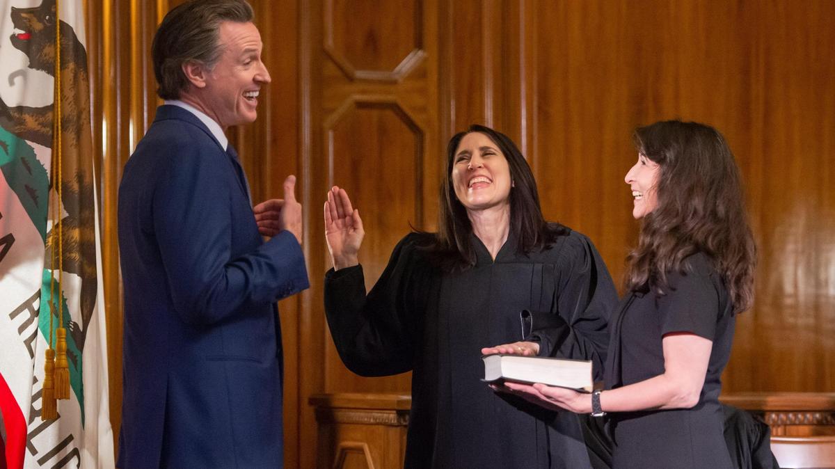 La nueva magistrada superior de la Corte Suprema Patricia Guerrero, en el centro, comparte unas risas con el gobernador Gavin Newsom, a la izquierda, y su hermana Claudia Pearson, a la derecha, durante su juramento, el lunes 2 de enero de 2023, en la Biblioteca Stanley Mosk y el Edificio de Tribunales en el centro de Sacramento.