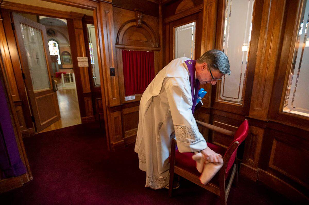 At the beginning of the pandemic, Father Michael O’Reilly disinfects the chair in the confessional at the Cathedral of the Blessed Sacrament in downtown Sacramento in April 2020.