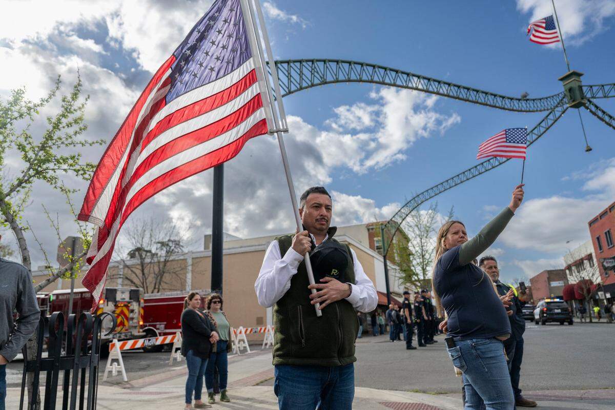 Yuba City resident Rigo Diaz waves an American flag to honor fallen Marysville police officer Osmar Rodarte on Thursday, March 27, 2025, during a procession from the Lakeside Colonial Chapel through downtown Marysville to Placer County.