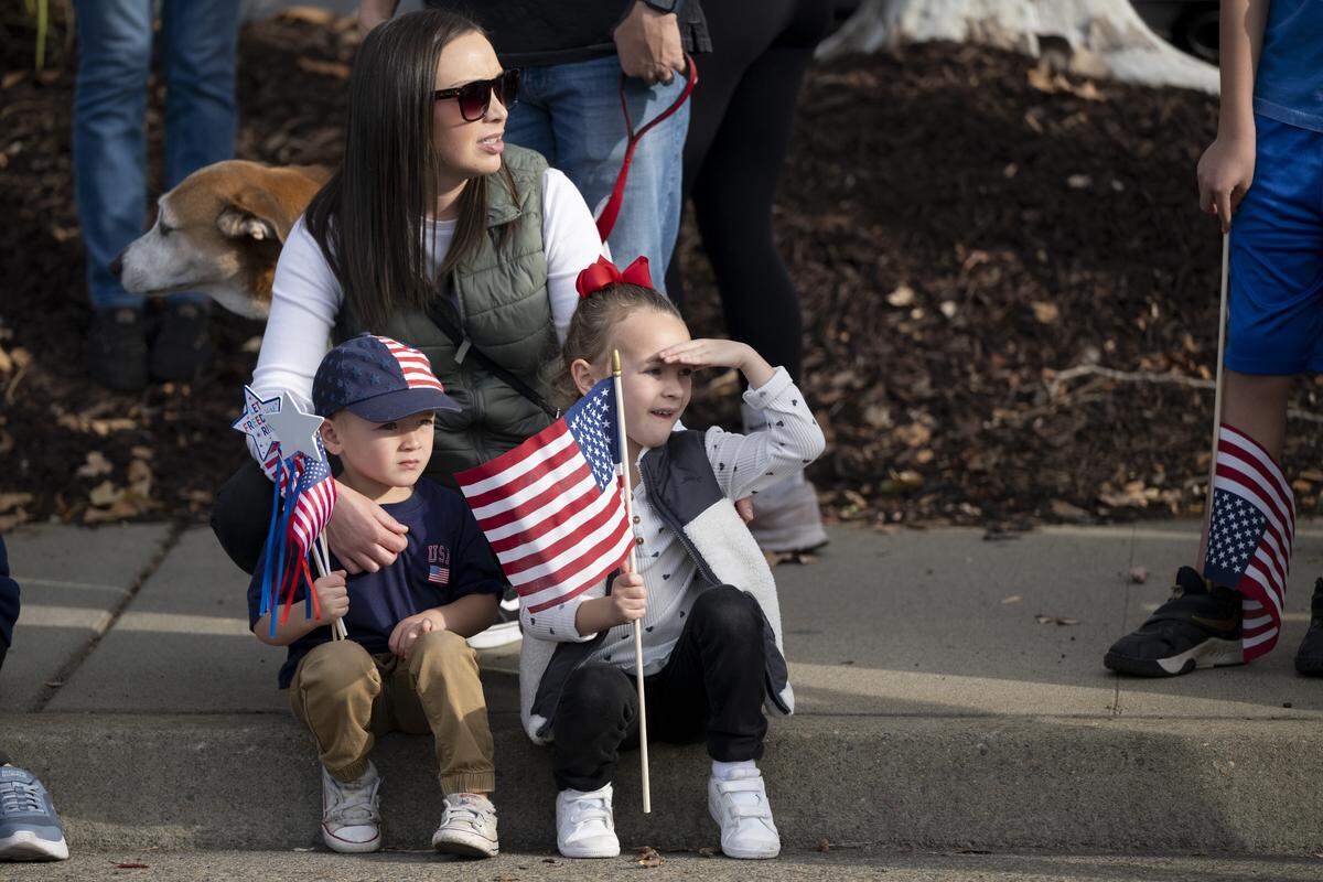 Families wave American flags during a Veterans Day parade in Folsom on Tuesday, Nov. 11, 2025.