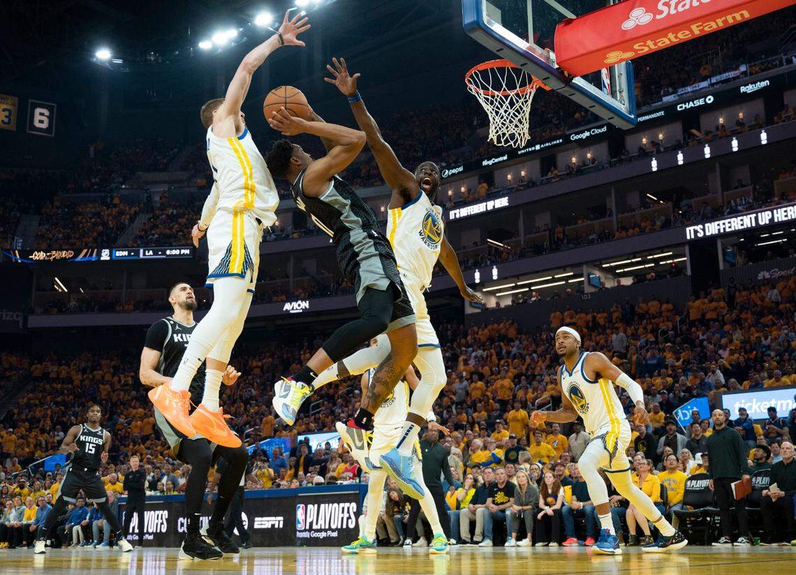 Sacramento Kings guard Malik Monk (0) shoots a basket between Golden State Warriors guard Donte DiVincenzo (0) and forward Draymond Green (23) during Game 4 of the first-round NBA playoff series at Chase Center in San Francisco on Sunday.