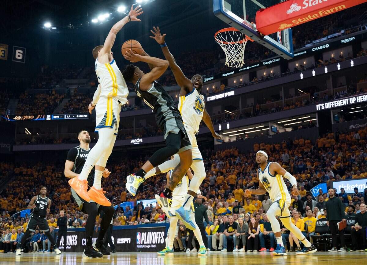 Sacramento Kings guard Malik Monk (0) shoots a basket between Golden State Warriors guard Donte DiVincenzo (0) and forward Draymond Green (23) during Game 4 of the first-round NBA playoff series at Chase Center in San Francisco on Sunday.