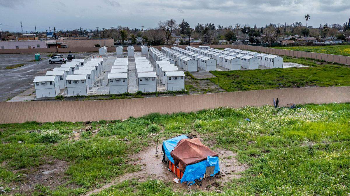 Homeless people set up ther camp just outside the unoccupied pallet cabin village on March 22, 2023. The tiny homes were assembled last summer. The site at Florin and Power Inn roads has 100 single and double-occupancy cabins, bathrooms and communal gathering spaces.