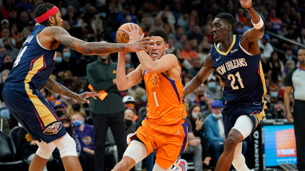 Phoenix Suns guard Devin Booker (1) drives as New Orleans Pelicans forward Tony Snell (21) defends during the second half of an NBA basketball game, Friday, Feb. 25, 2022, in Phoenix. (AP Photo/Matt York)