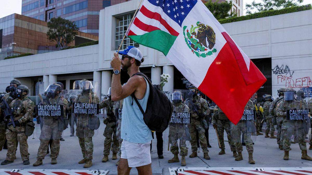 Protester Tim Croghan carries U.S. and Mexican flags while demonstrating in front of the California National Guard at the federal building in downtown Los Angeles on June 12.