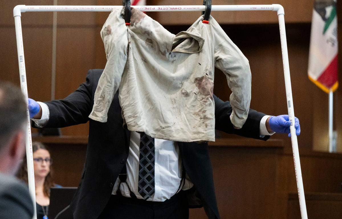 Davis Police Department detective Alex Torres moves a sweater that was worn by David Breaux who was allegedly stabbed to death by former UC Davis student Carlos Reales Dominguez, during the first day of trial at Yolo Superior Court in Woodland on Monday.