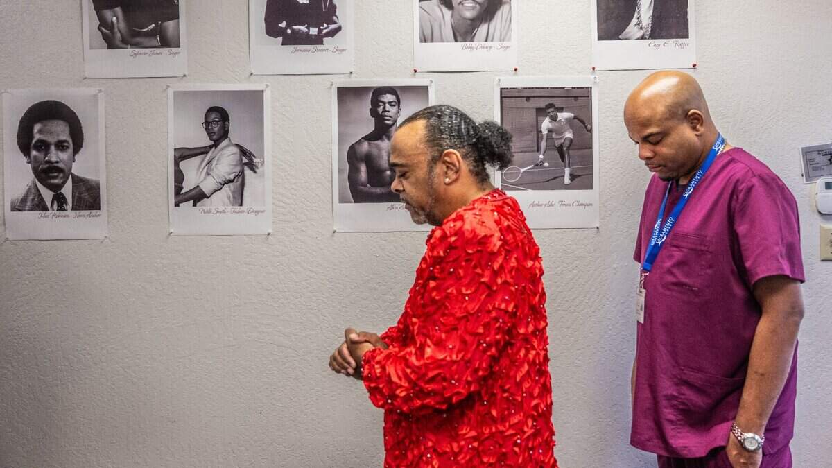 Clarmundo Sullivan, founder of nonprofit Golden Rule Services, and executive assistant NeGel Robinson participate in an open prayer as they host a 35th World AIDS Day commemoration in south Sacramento on Friday. Posted on the wall are photographs of notable people of color who had HIV, such as tennis star Arthur Ashe Jr. Sullivan’s organization was founded in 2000 with a focus on reducing HIV-related health disparities among people of color.
