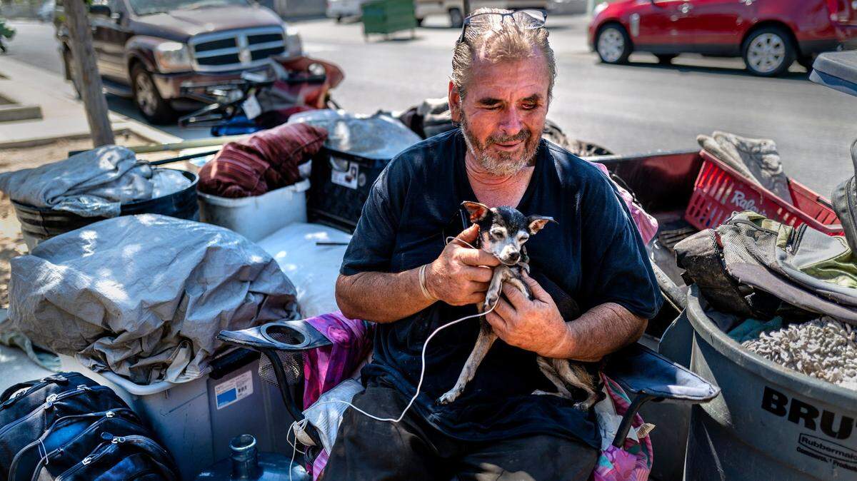 Fred Gurr, 58, suffering from the loss of his left eye, sits with his Chihuahua Chompers among all of his belongings Wednesday, May 25, 2022. near Lexington Street and Dixieanne Avenue in Old North Sacramento where he was staying in a shack in a homeless encampment before a tow truck towed it away earlier in the day. He said he was hoping to get into one of the city’s tiny homes.