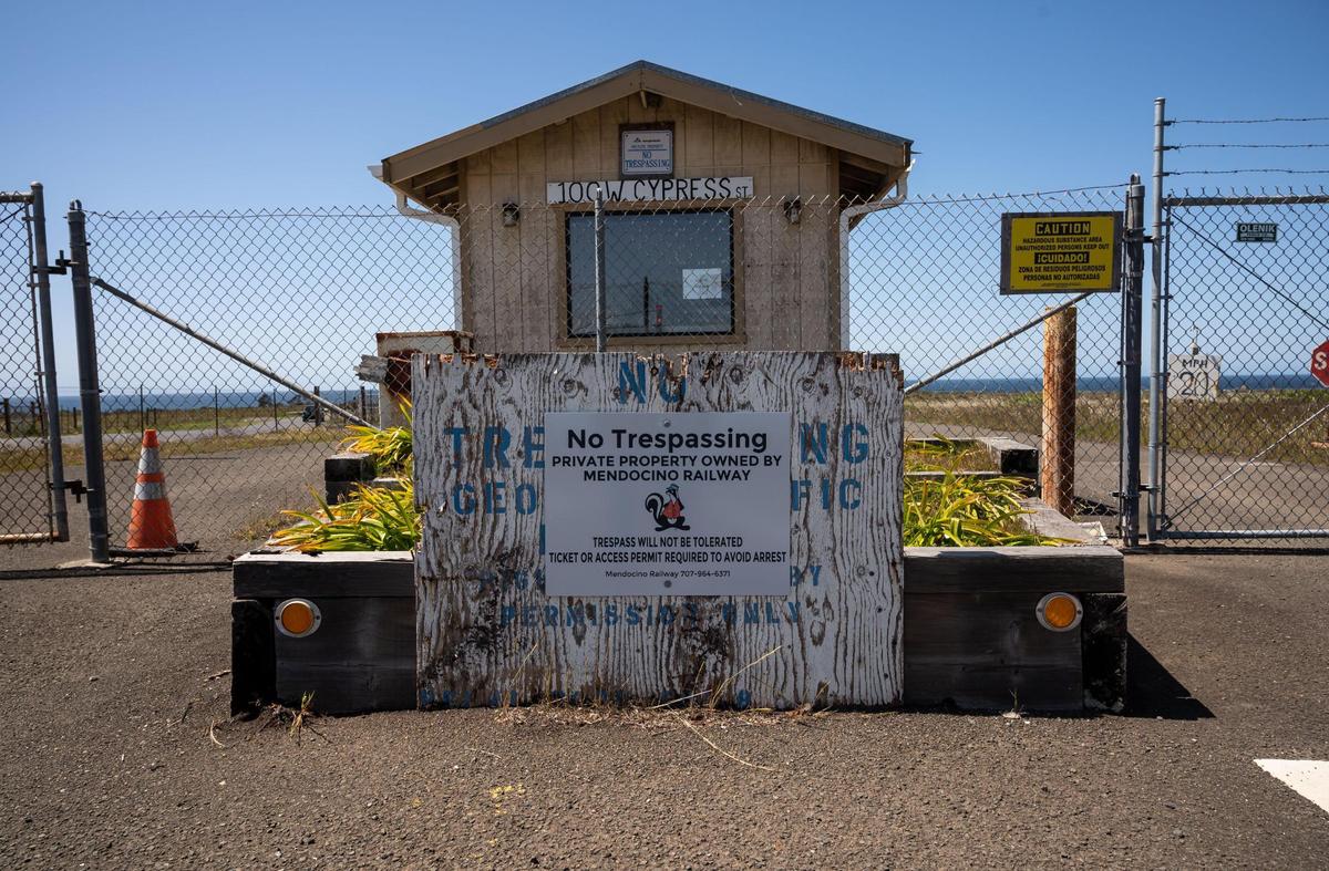 A “no trespassing” sign from Mendocino Railway is seen over a similar sign from Georgia-Pacific’s era of ownership at a former guard shack for an entry to the old mill site on April 16 in Fort Bragg. The fenced off land, acquired by the the Skunk Train’s parent company in November 2021, borders the California Coastal Trail along the Pacific Ocean.