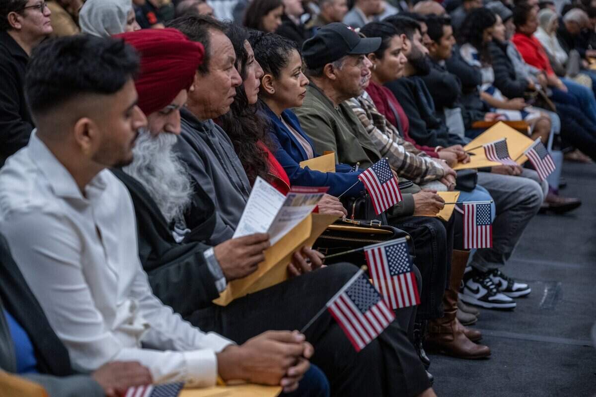 New U.S. citizens hold American flags during a U.S. Citizenship and Immigration Services naturalization ceremony At the Grounds in Roseville on Wednesday, Dec. 20, 2023.