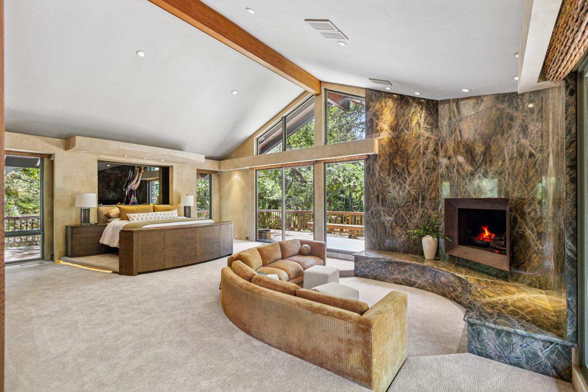 A sunken living area with a fireplace anchors the primary suite.