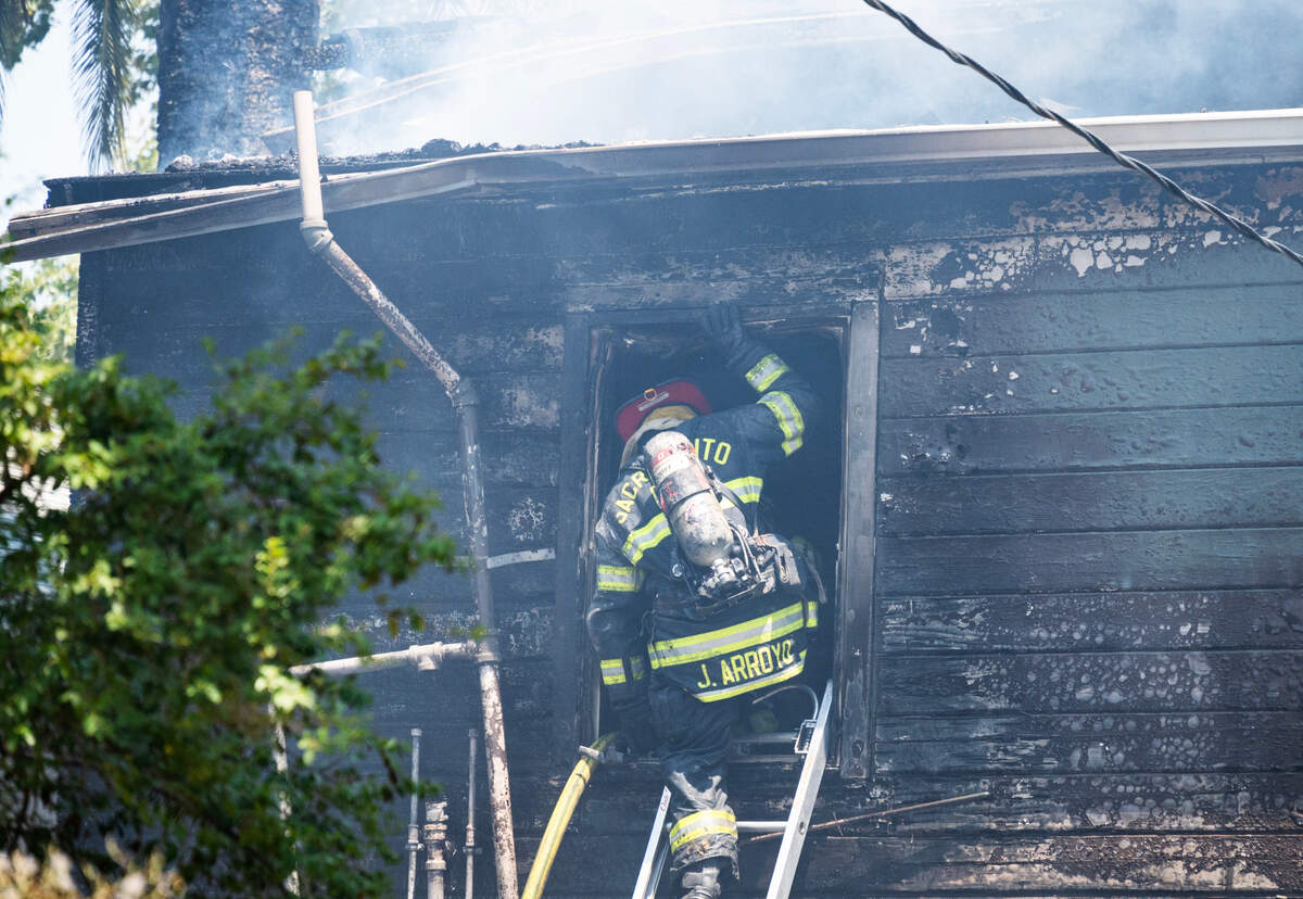 A Sacramento firefighter climbs into the window of a burned apartment building on T Street in Sacramento on Friday, July 12, 2024.