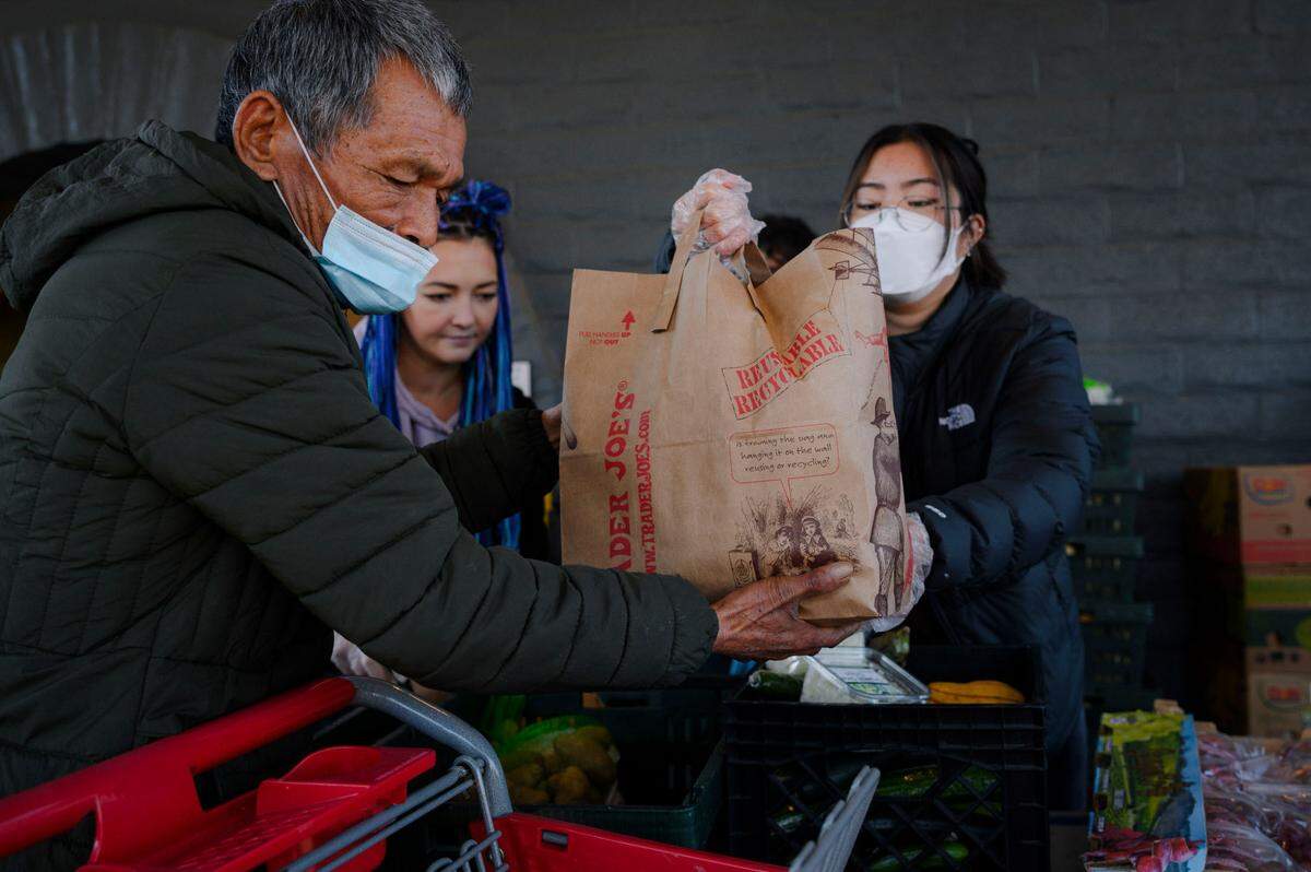 Volunteer Winnie Liao hands a bag of fruits and vegetables to a senior customer at River City Food Bank in Sacramento in December. A number of barriers, including misinformation about who is eligible, may discourage older people from enrolling in CalFresh.