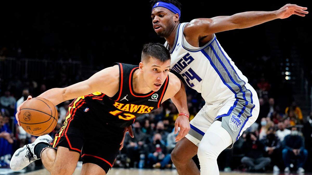 Atlanta Hawks guard Bogdan Bogdanovic (13) drives against Sacramento Kings guard Buddy Hield (24) in the first half of an NBA basketball game Wednesday, Jan. 26, 2022, in Atlanta. (AP Photo/John Bazemore)
