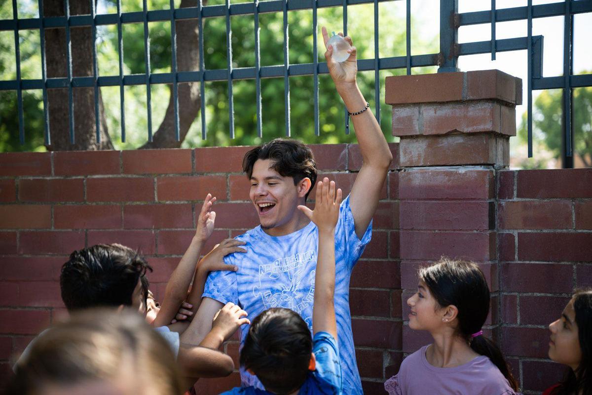 José Salazar, 18, a graduate of The Greenhouse youth program who returned to work there as a summer programming assistant, holds a water balloon up as he plays with kids in the program in South Natomas on Monday.