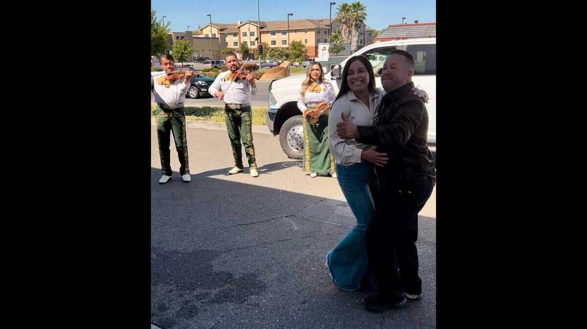 Miembros del Mariachi América de Sacramento tocan en el estacionamiento de una gasolinera local 76 mientras uno de los clientes baila con su pareja el domingo por la mañana.