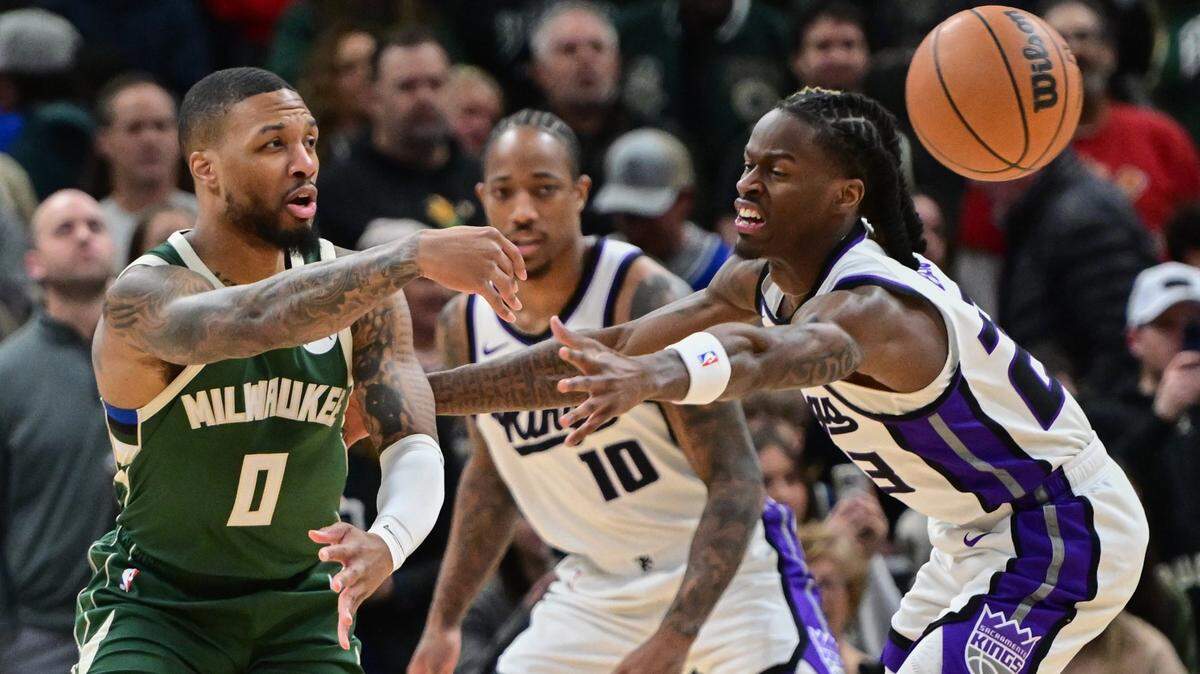 Jan 14, 2025; Milwaukee, Wisconsin, USA;  Milwaukee Bucks guard Damian Lillard (0) passes the ball away from Sacramento Kings forward DeMar DeRozan (10) and guard Keon Ellis (23) in the first quarter at Fiserv Forum. Mandatory Credit: Benny Sieu-Imagn Images