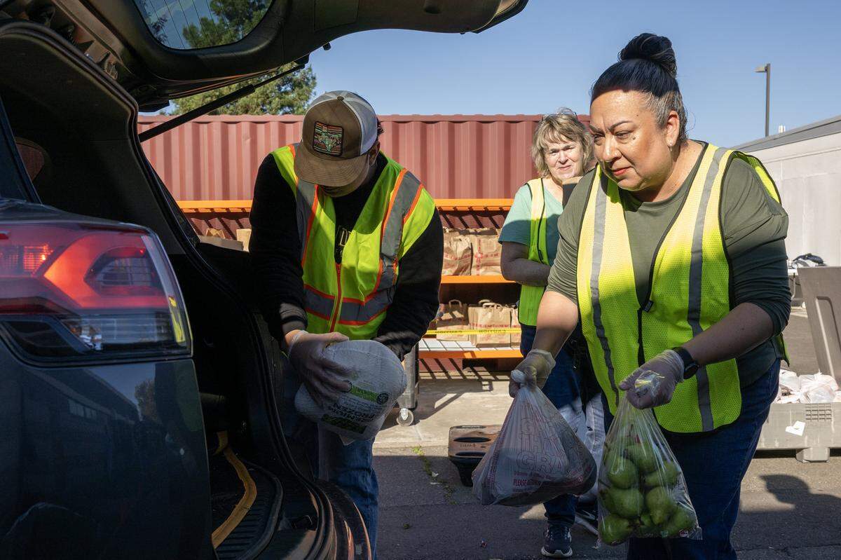 Gio Segura, Mary Shephard and Sabina Segura help distribute food with other volunteers at Joey’s Food Locker, a program run by the Natomas Unified School District, on Friday in Sacramento. The program is set to distribute Thanksgiving meals to more than 1,000 families.
