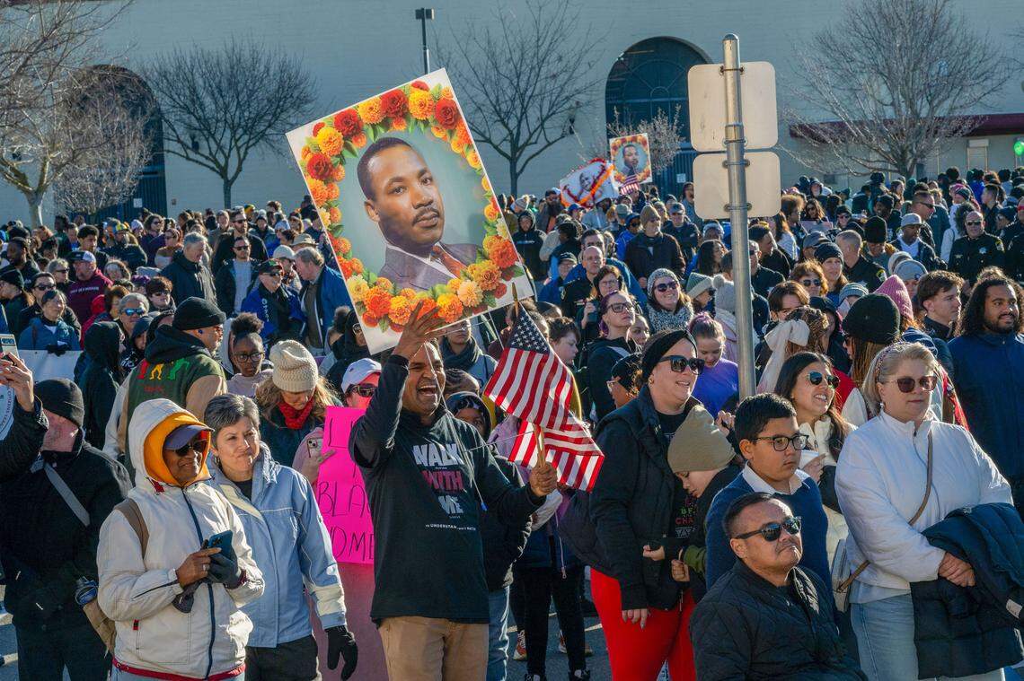 YK Chalamcherla, a Folsom Cordova Unified School District board member, holds American flags and a poster of Martin Luther King Jr. before the March for the Dream at Sacramento City College on Monday.