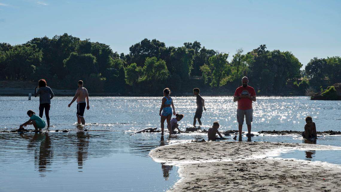 Families enjoy the water on a mid-90s summer day on the American River in Sacramento's Tiscornia Park on July 31.