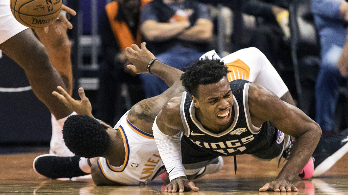 Sacramento Kings’ Buddy Hield (24) falls hard as he battles for a ball with Phoenix Suns’ Troy Daniels (30) during the first half of an NBA basketball game, Tuesday, Dec. 4, 2018, in Phoenix. (AP Photo/Darryl Webb)