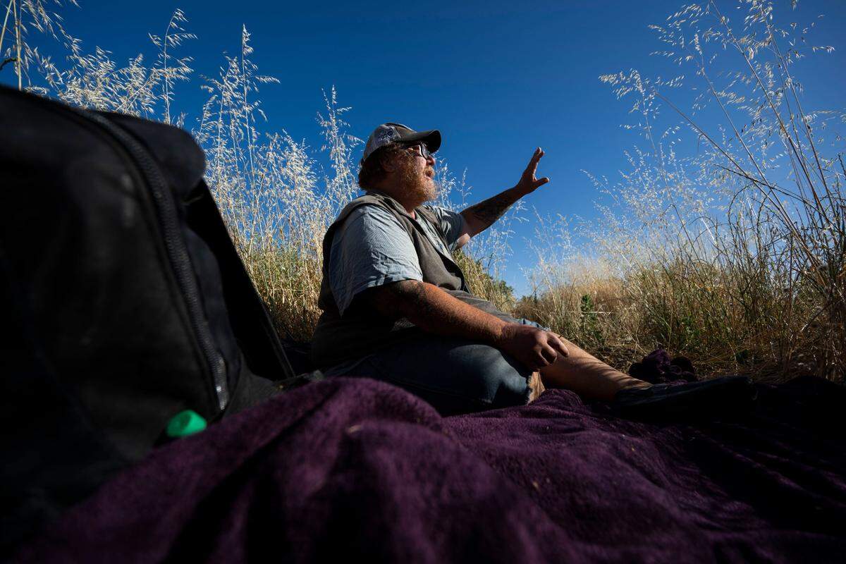 Paul Jackson describes the view from his camp site near the American River last month. Jackson has benefited from the assistance of social workers at the Sacramento Public Library.