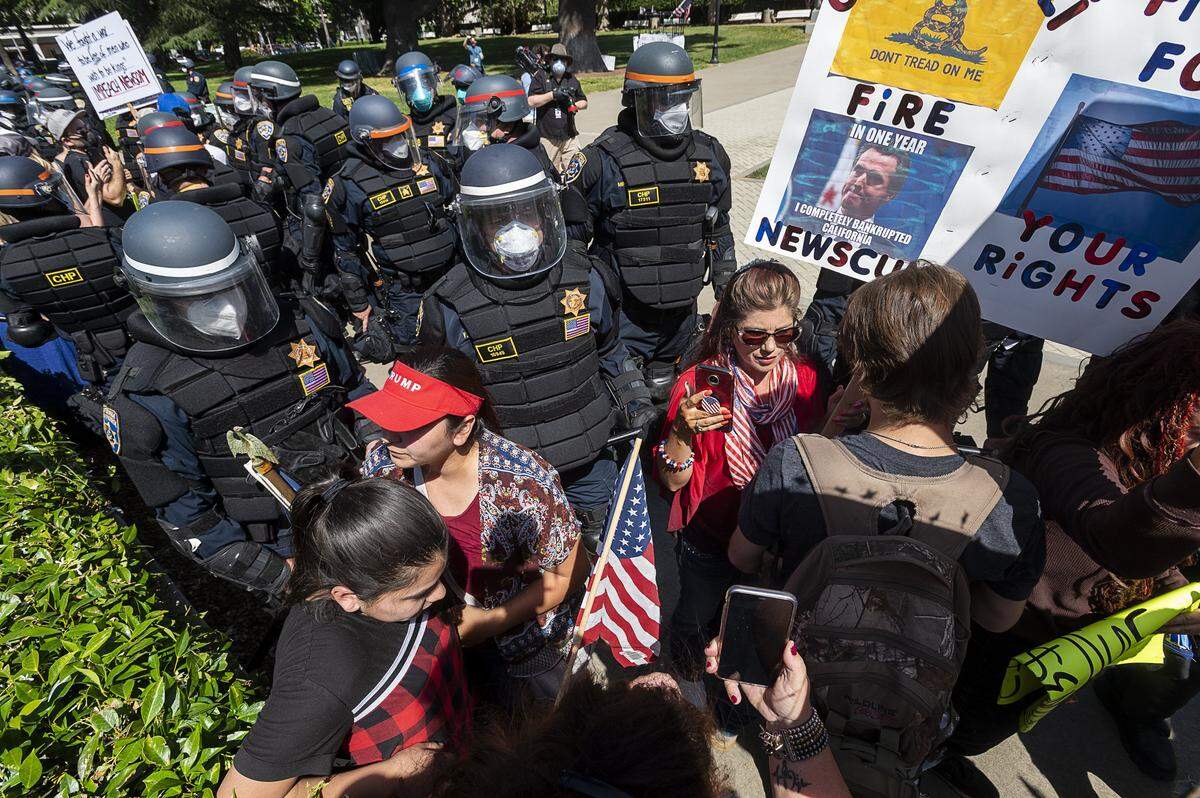 Califiornia Highway Patrol Officers move protesters back at a demonstration at the Capitol in Sacramento on Friday, May 1, 2020, against Gov. Gavin Newsom’s stay-at-home order to slow the spread of the coronavirus.